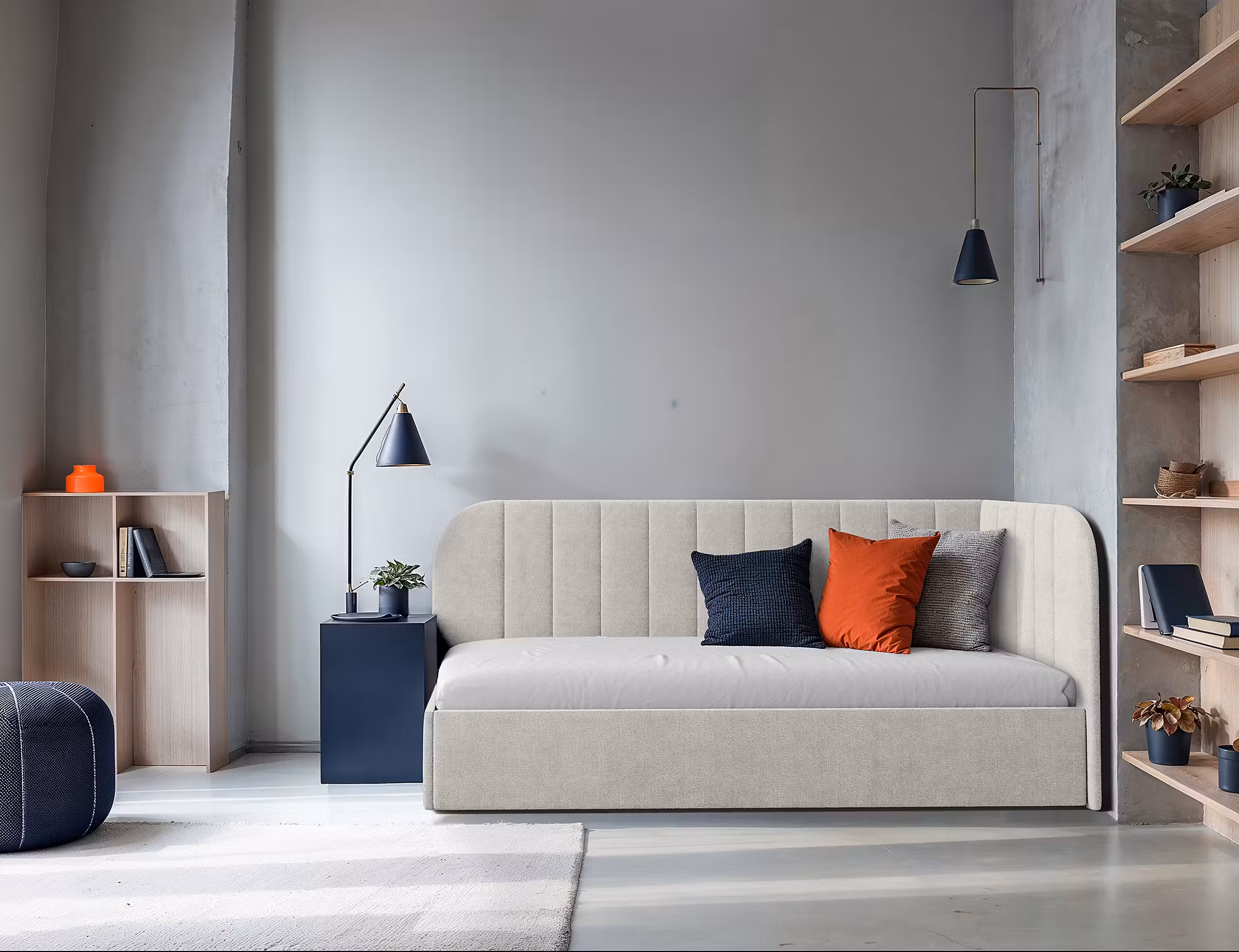 Hellgraues Schlafsofa mit bunten Kissen, dazu stylishe Leuchten im Industrial-Retro-Design..