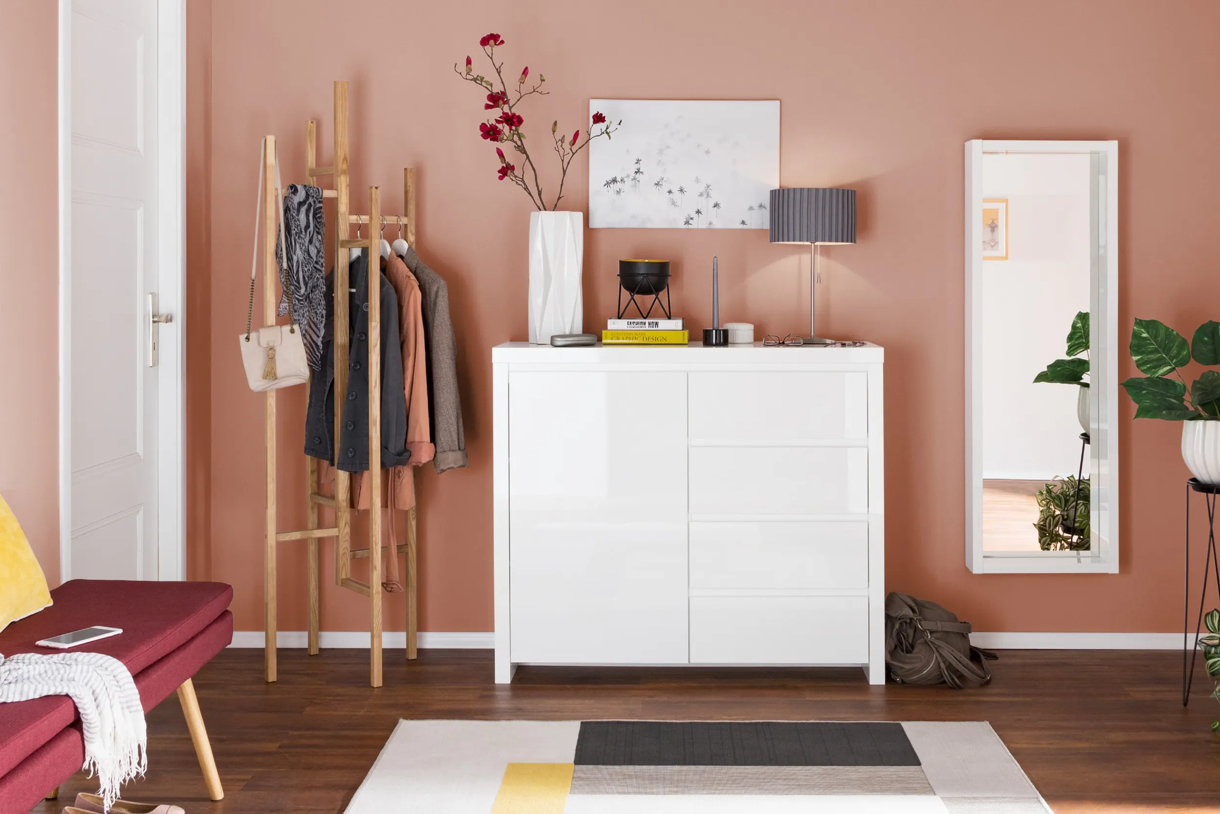 Wit kastje met staande kapstok spiegel tegen roze wand