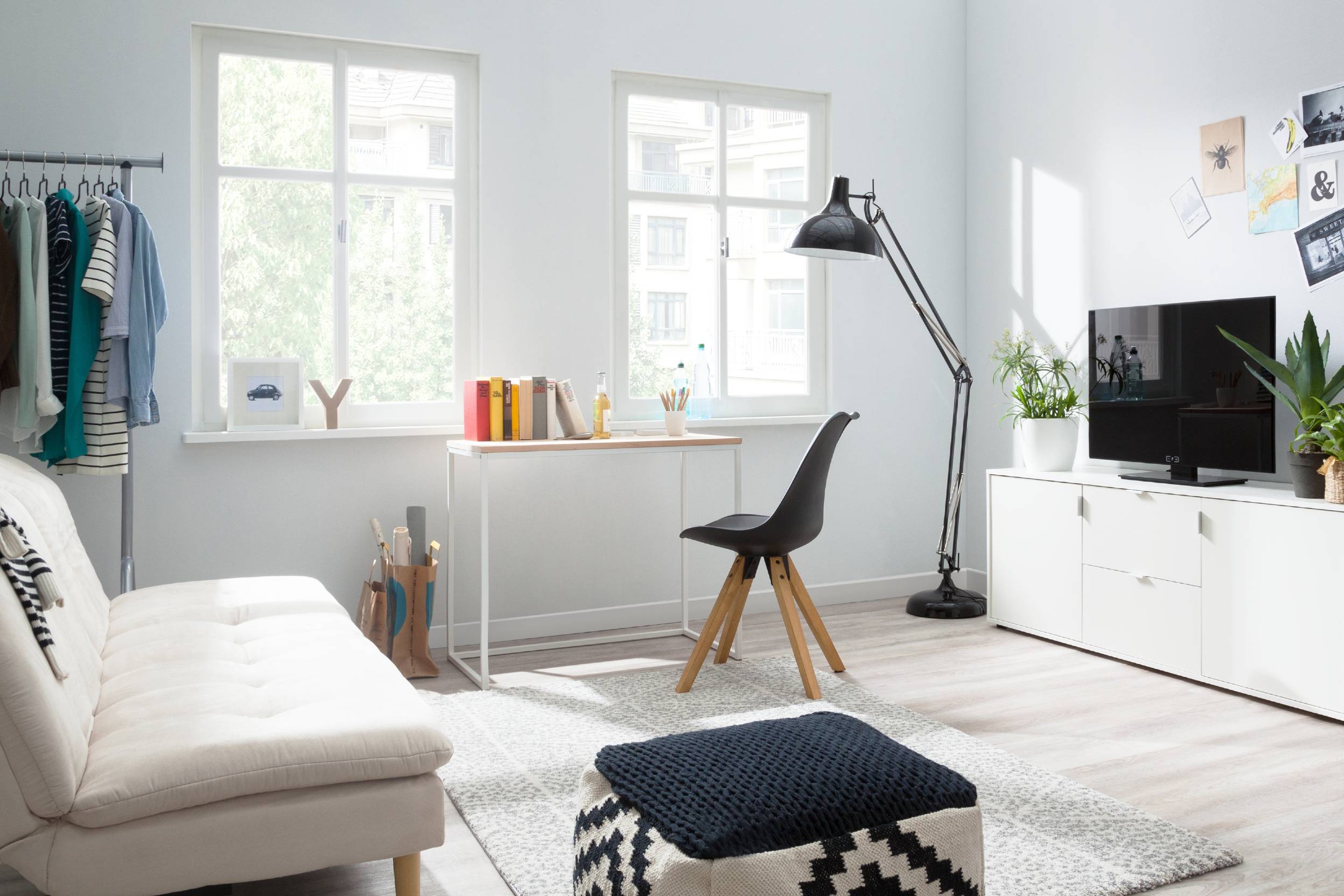 Zimmer mit Fernseher, Schlafsofa, Schreibtisch und Kleiderstange