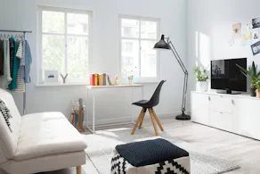 Zimmer mit Fernseher, Schlafsofa, Schreibtisch und Kleiderstange