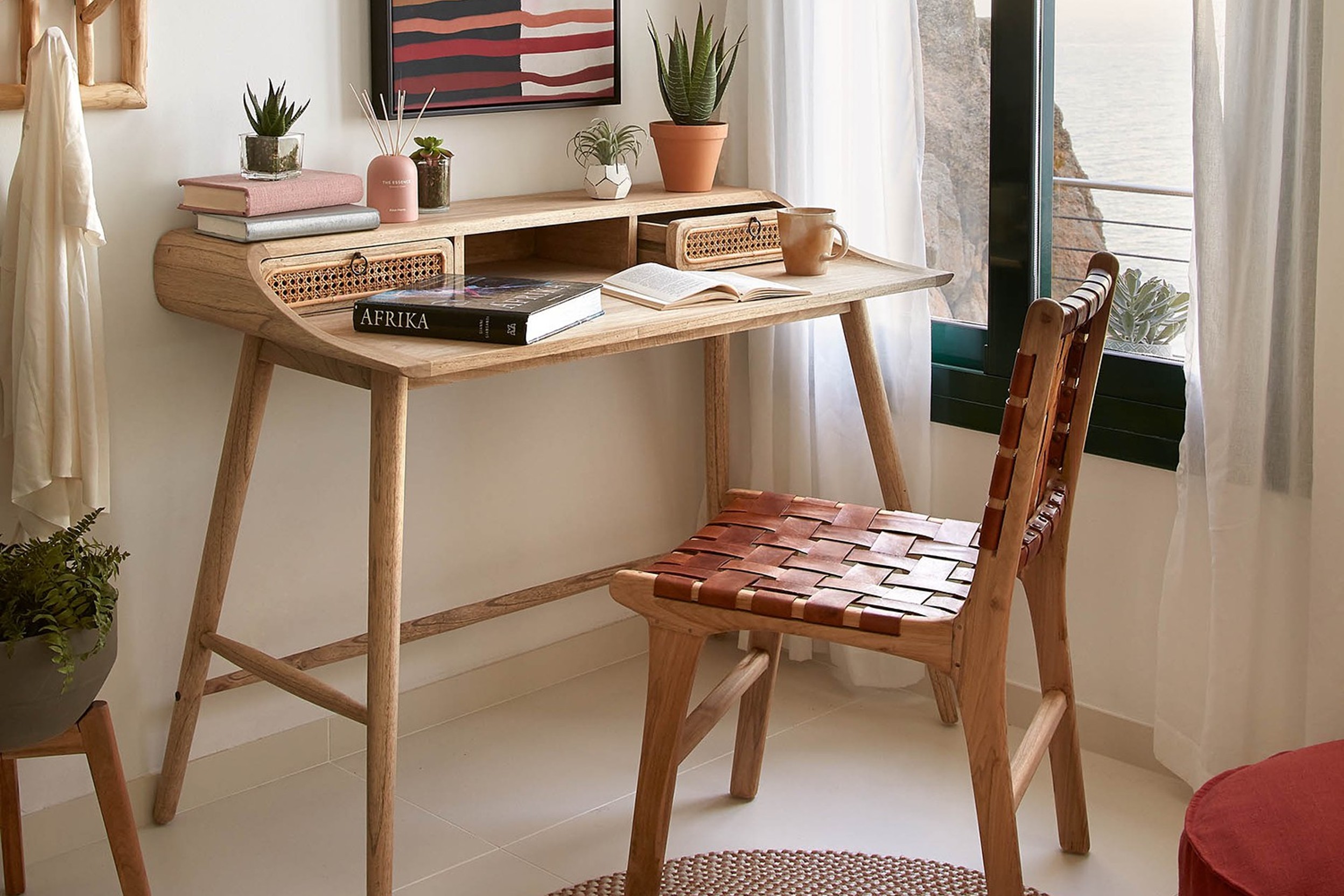 Kompakter Schreibtisch mit Rattan-Details, Pflanzen und weiteren Deko-Gegenständen