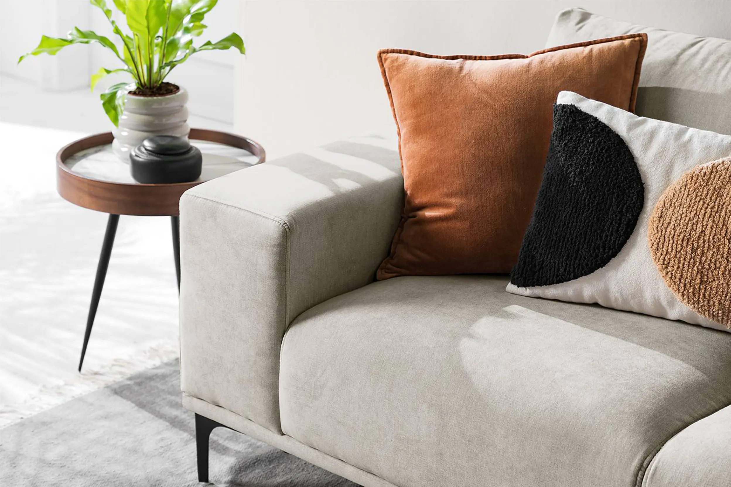 Eine Nahaufnahme eines grauen Microfaser-Sofas mit Dekokissen und einem Beistelltisch
