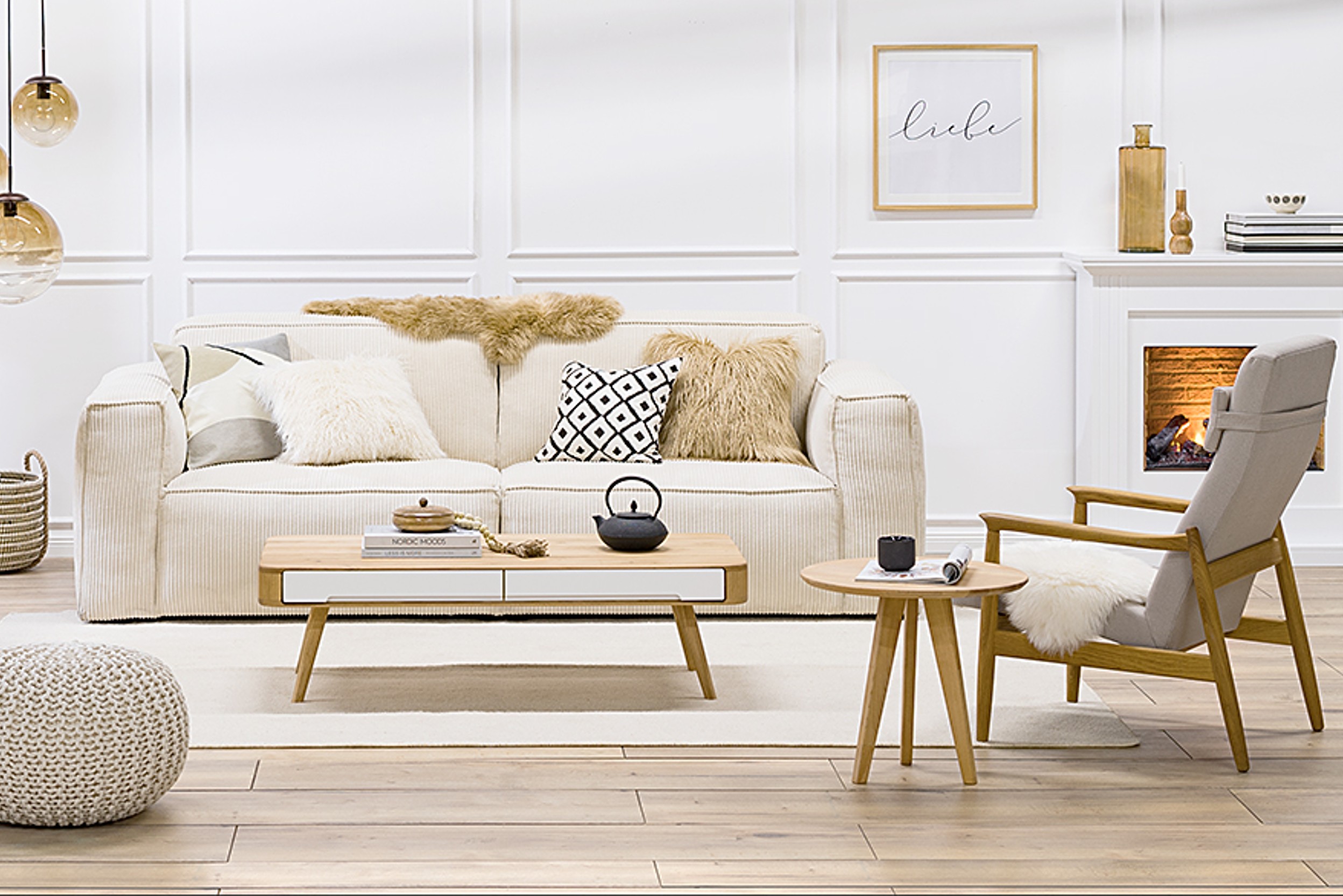 Sitzbereich im Wohnzimmer mit Kamin, Sofa, 2 Sesseln, 2 Tischen und diversen Textilien