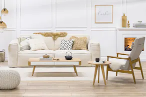Sitzbereich im Wohnzimmer mit Kamin, Sofa, 2 Sesseln, 2 Tischen und diversen Textilien