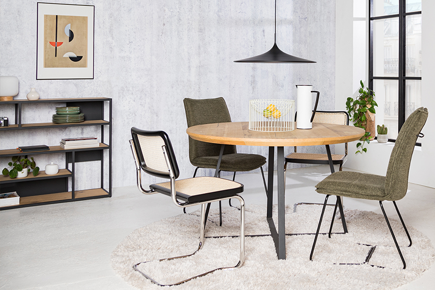 Esszimmer bestehend aus Freischwingern mit Wiener Geflecht und Stühlen aus Chenille-Stoff, dazu Regale im Industrial-Stil, ein weißer Teppich, eine schwarze Pendelleuchte sowie ein Wandbild und Deko.