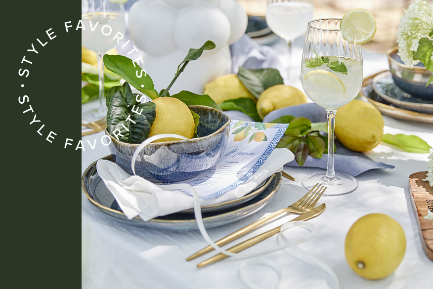 Gedeckter Tisch mit Limoncello Spritz in geriffelten Gläsern von BUTLERS, dazu goldenes Besteck, blaugraues Geschirr und saftige Zitronen zur Deko.