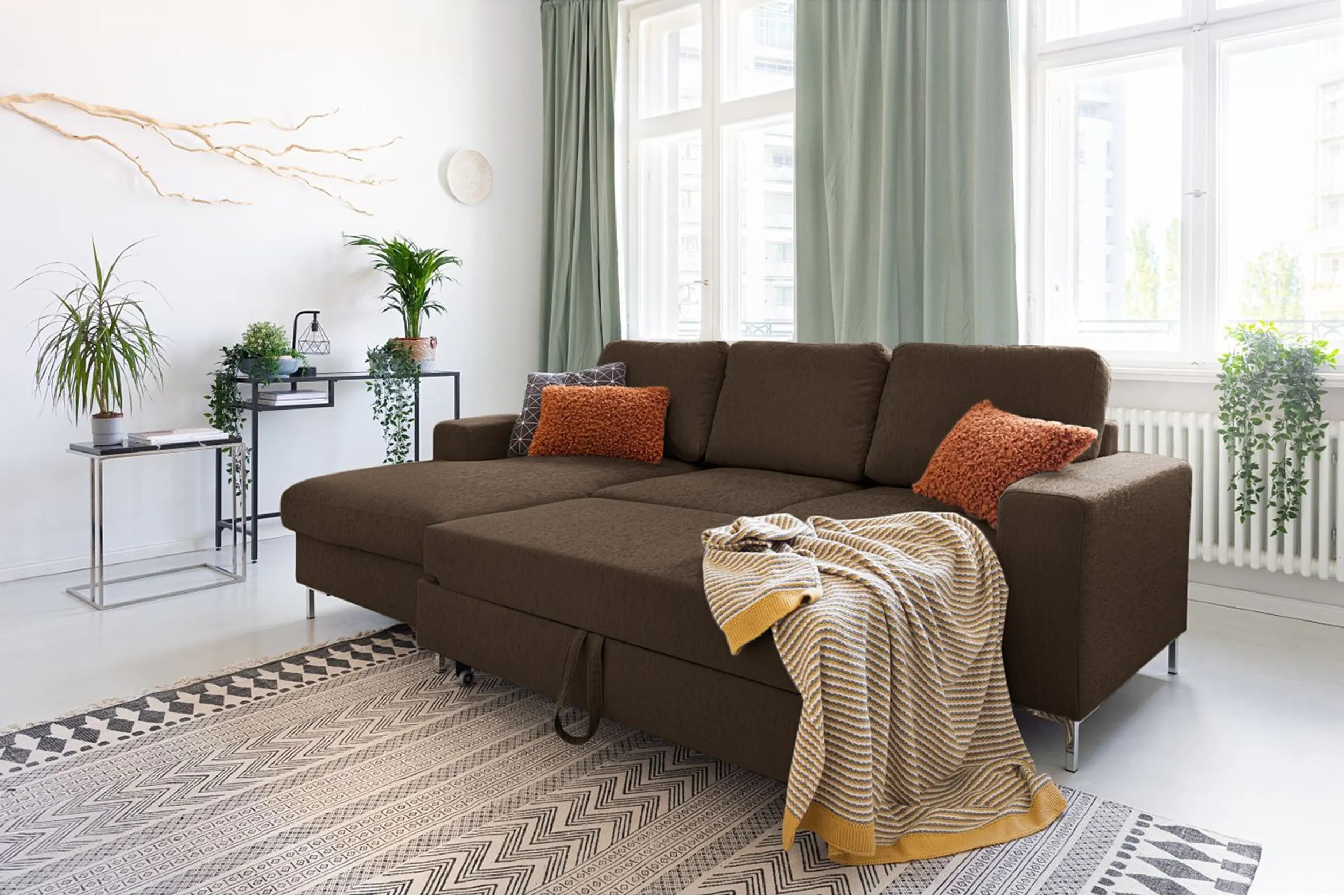 Geräumiges Schlafsofa in Braun mit rostfarbenen Kissen und gestreifter Decke