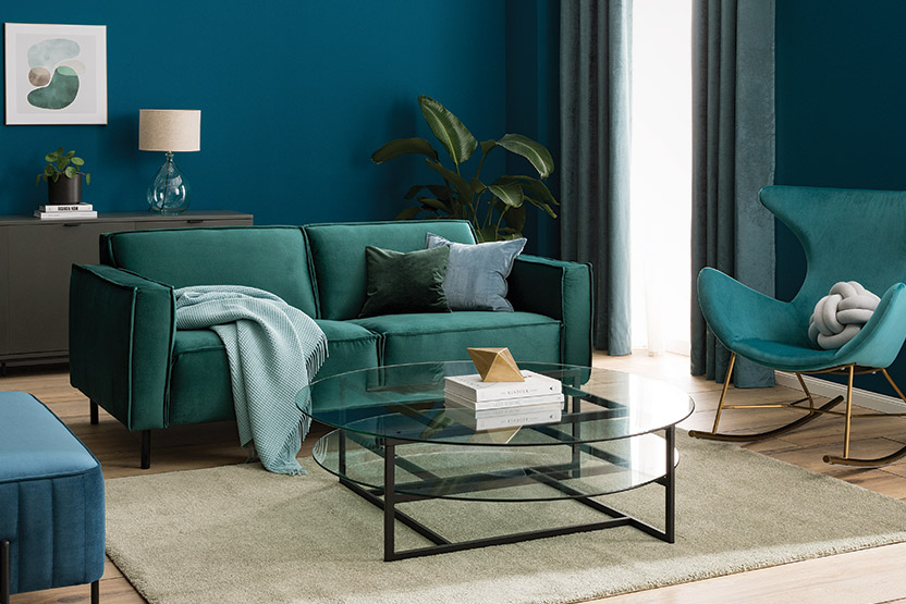 Wohnzimmer in Grüntönen mit grünem Samtsofa und Schaukelsessel aus Samt und Glastisch
