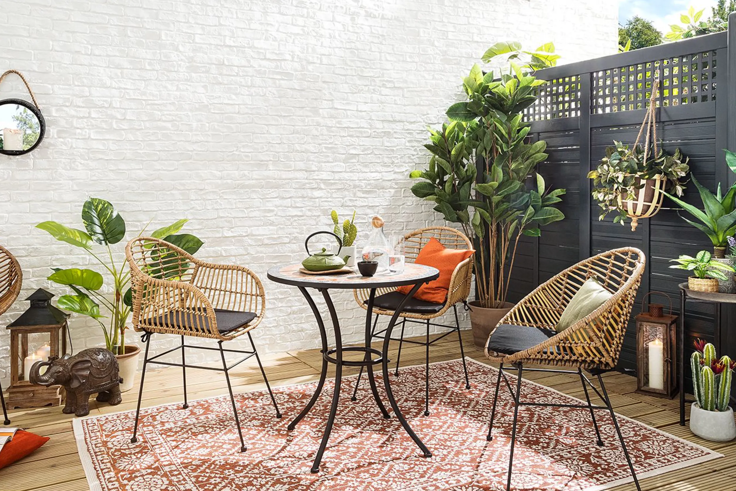 Rattanstühle, Bistrotisch aus Metall und Outdoor-Teppich auf wohnlicher Terrasse