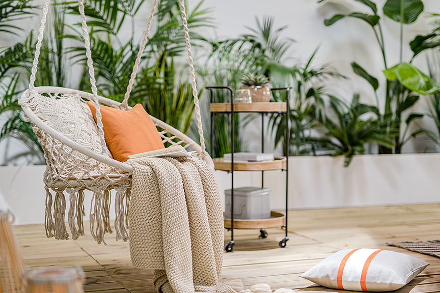 Beige hangstoel in de Boho stijl met beige deken en oranje kussen