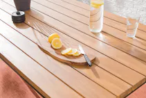 Detailaufnahme eines Gartentisches aus Holz mit aufgeschnittenen Zitronenscheiben