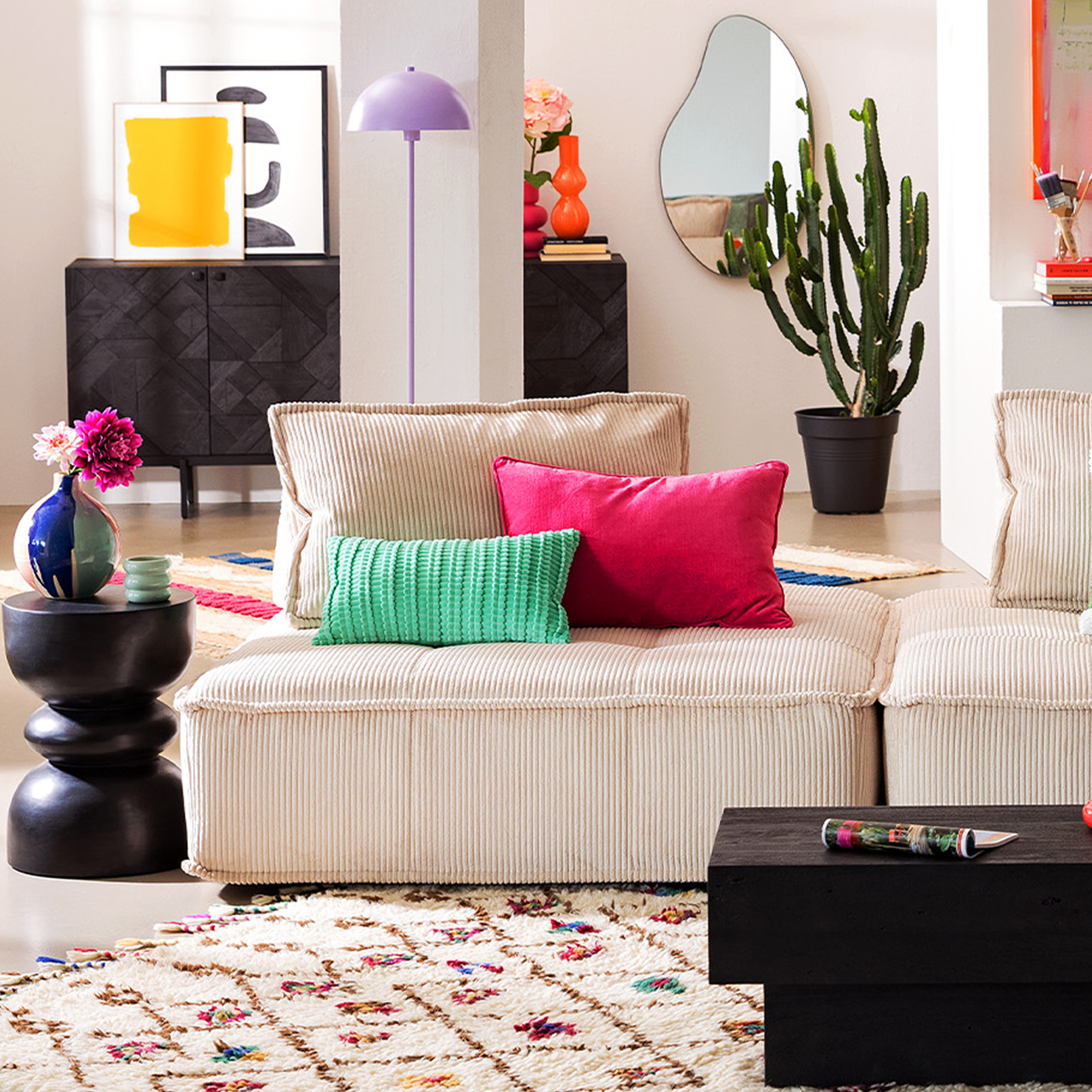 Großes, beiges Sofa mit bunten Kissen und farbenfroher Deko.