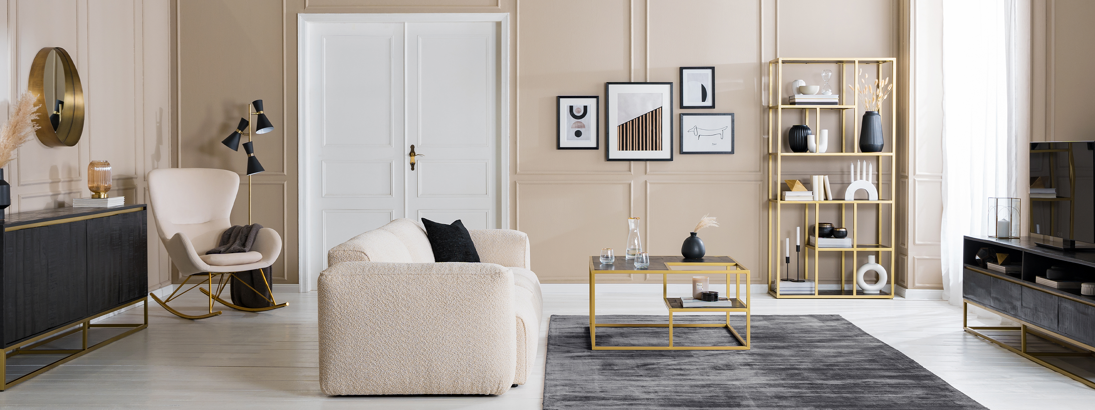 Salon avec canapé et fauteuil beiges, table basse, étagère et enfilade noires avec structure en métal doré, objets décoratifs blancs, tapis et coussins