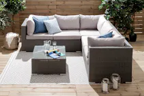 Gartenecksofa aus Polyrattan mit Tisch, Kissen und Outdoor-Teppich