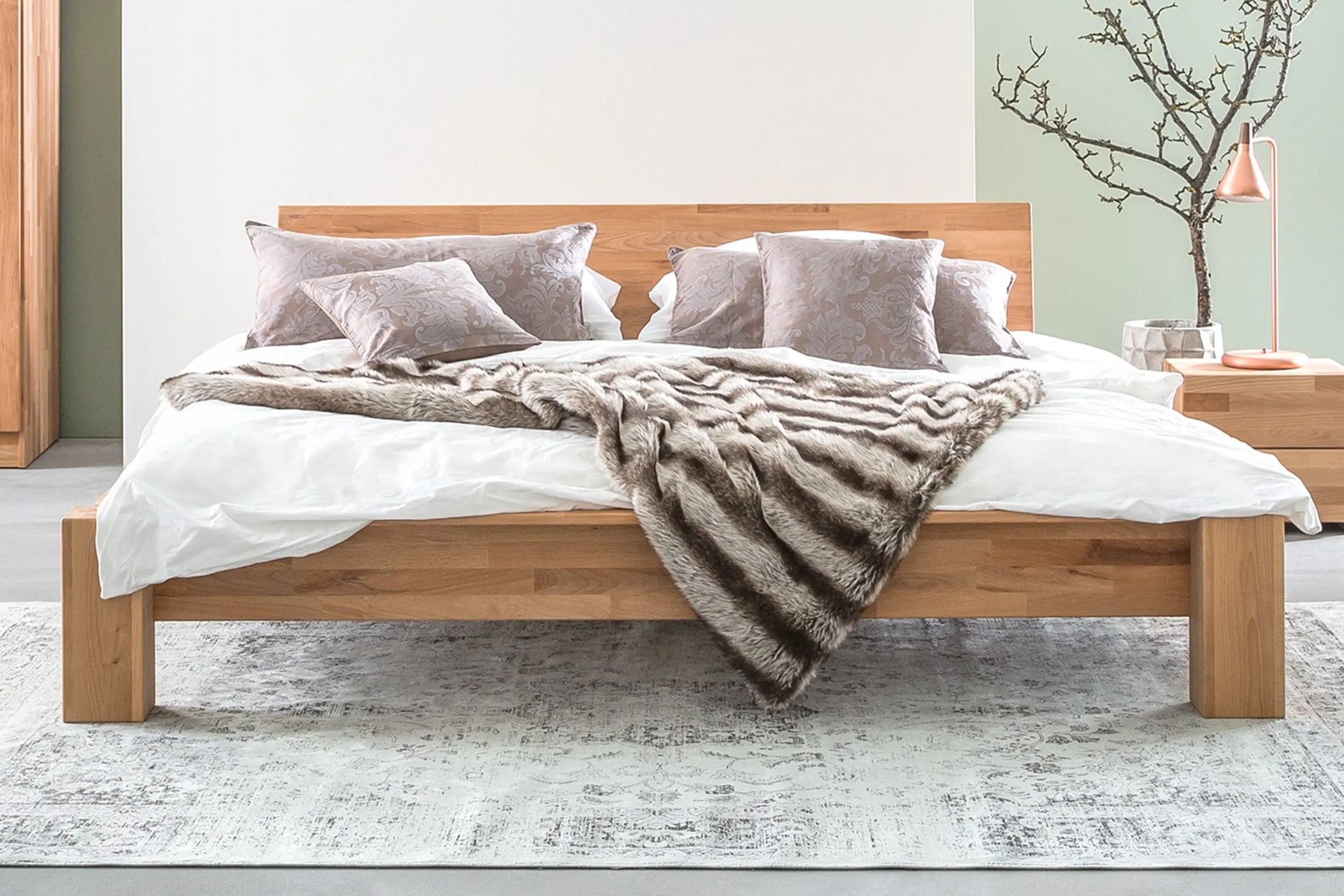 Fotonbett mit Kopfteil aus Holz mit edlen Kissen und Tagesdecke aus Fell