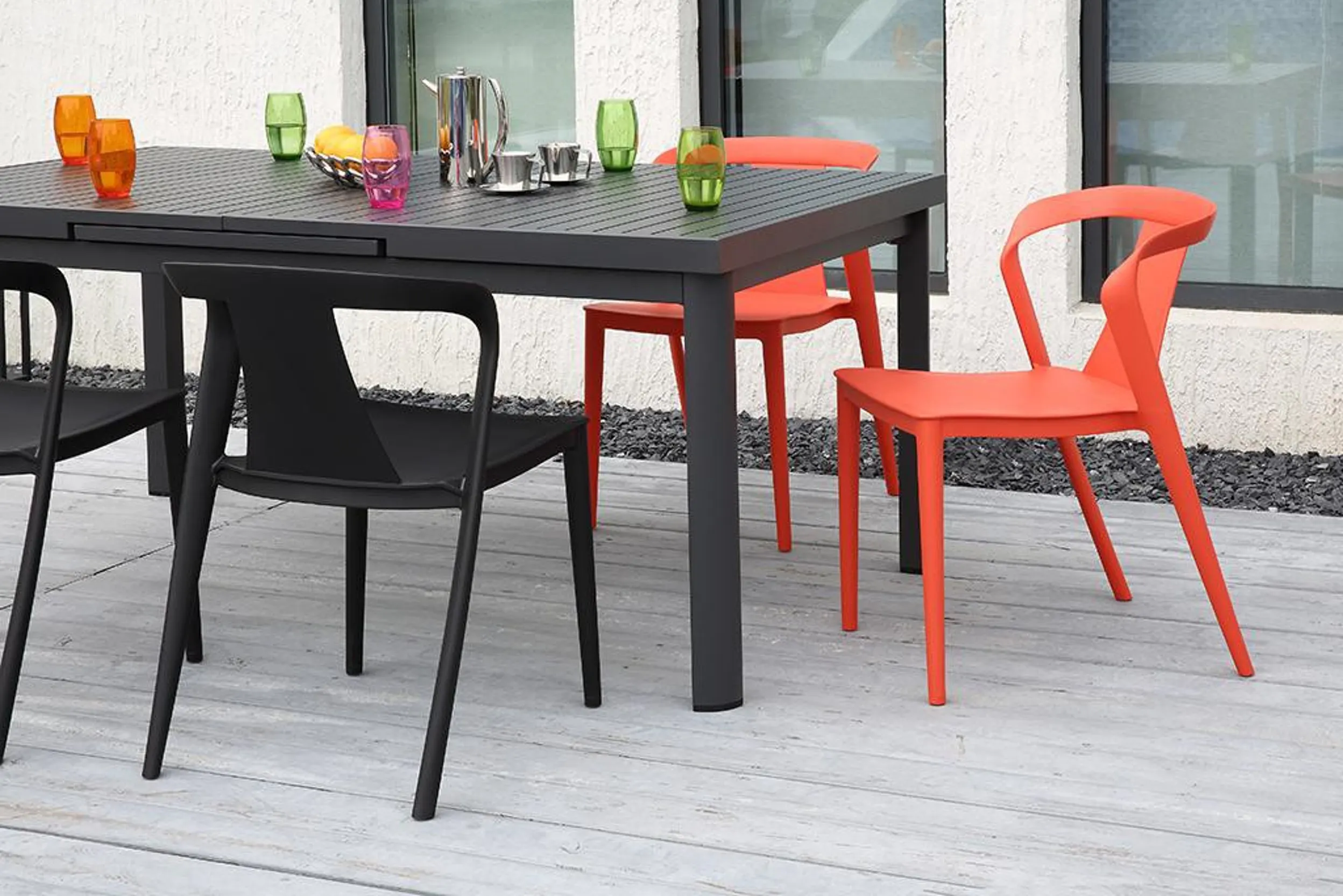 Ausziehbarer schwarzer Gartentisch mit schwarzen und roten Kunststoffstühlen