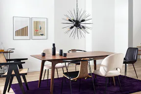 Esszimmer im Retro-Stil mit dunklen Holzmöbeln, einem Stuhl mit Wiener Geflecht, einer Sputnik-Pendelleuchte, einem Servierwagen und Deko.