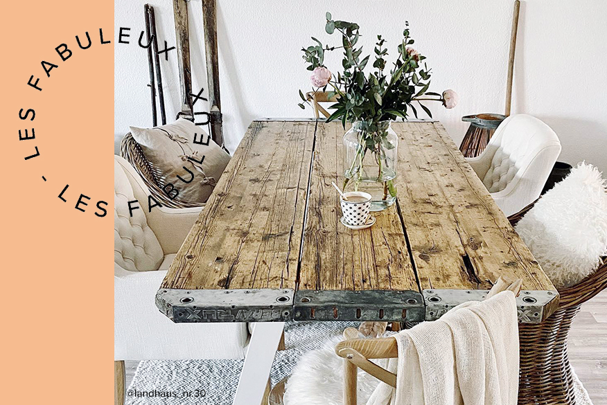 Salle à manger de style maison de campagne avec table en bois brut non traité, chaises en rotin foncé et chaises Chesterfield blanches ; à côté : table de salle à manger avec plateau en bois et chaises capitonnées grises de style scandinave.