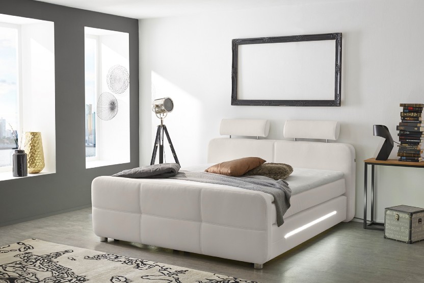 Gepolstertes Boxspringbett in Schlafzimmer mit großen Sitzfenstern