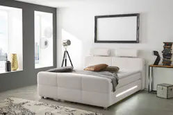 Gepolstertes Boxspringbett in Schlafzimmer mit großen Sitzfenstern