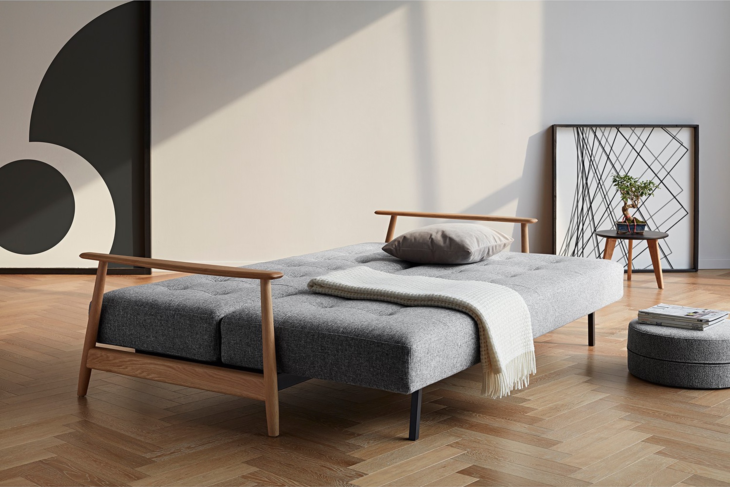 Graues Schlafsofa im skandinavischen Stil mit farblich abgestimmten Polsterhocker