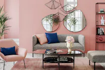 Wohnzimmer in rosa Pastellfarben mit großen Wandspiegeln im 3er-Set, gemütlicher Couchgarnitur und modernem Glas-Couchtisch.