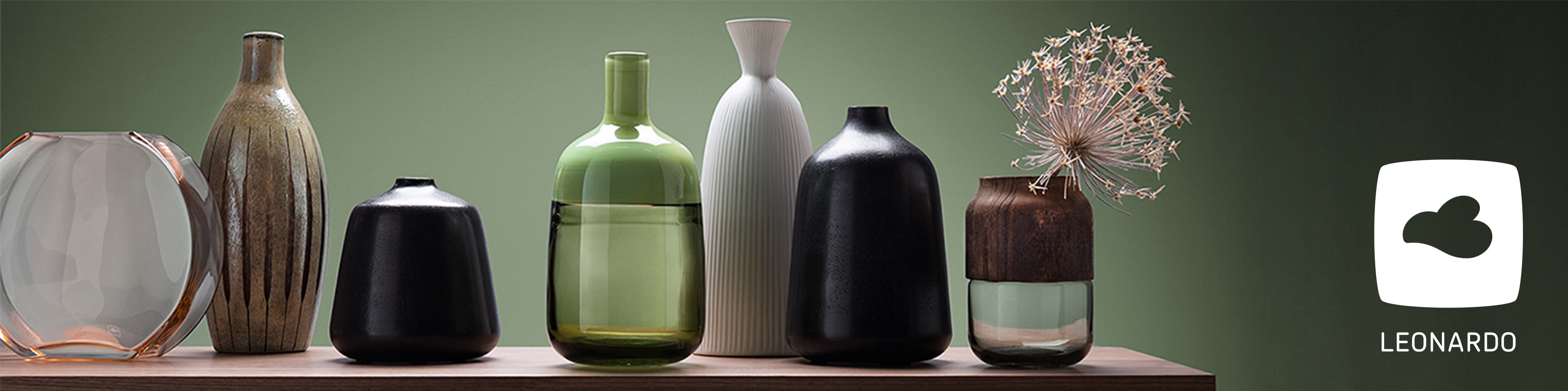 Farbige Vasen in verschiedenen Größen und Formen vor grüner Wand mit Leonardo Logo vorne rechts