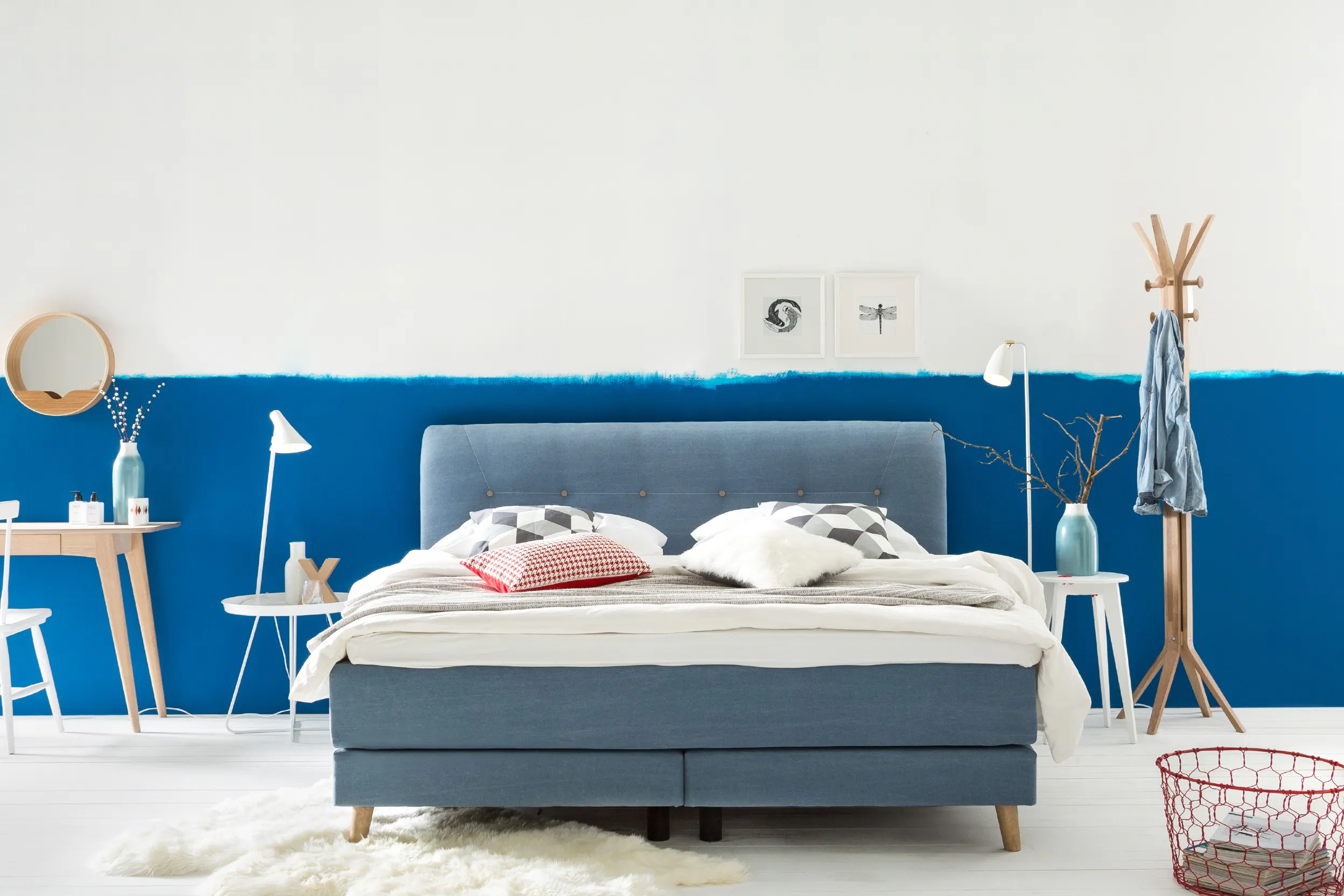 Chambre à coucher avec lit bleu, mur bleu et blanc, tapis blanc, petits meubles blancs ou en bois clair.