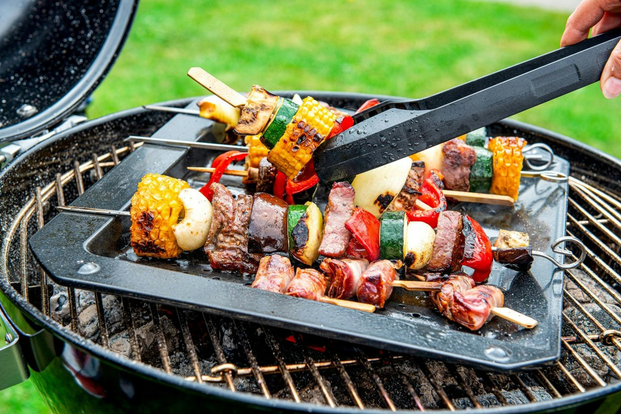 Grillrost mit einer mit Fleisch- und Gemüsespieße gefüllten Grillplatte