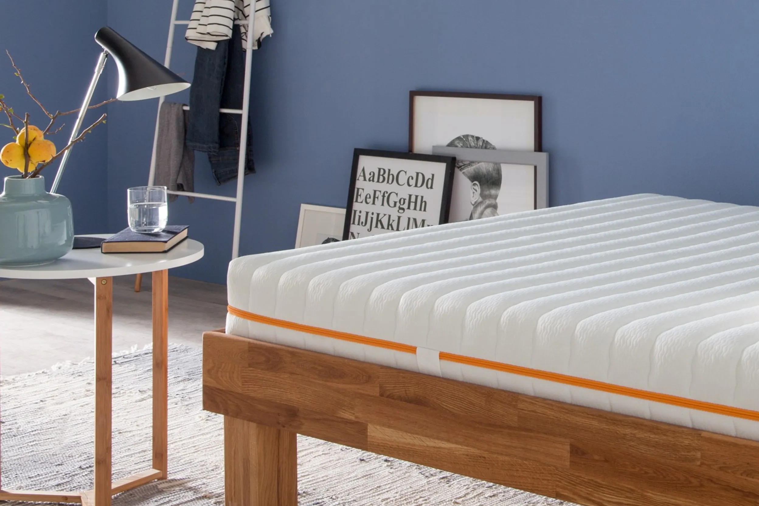 Holzbett mit Matratze in einem Zimmer mit blauen Wänden