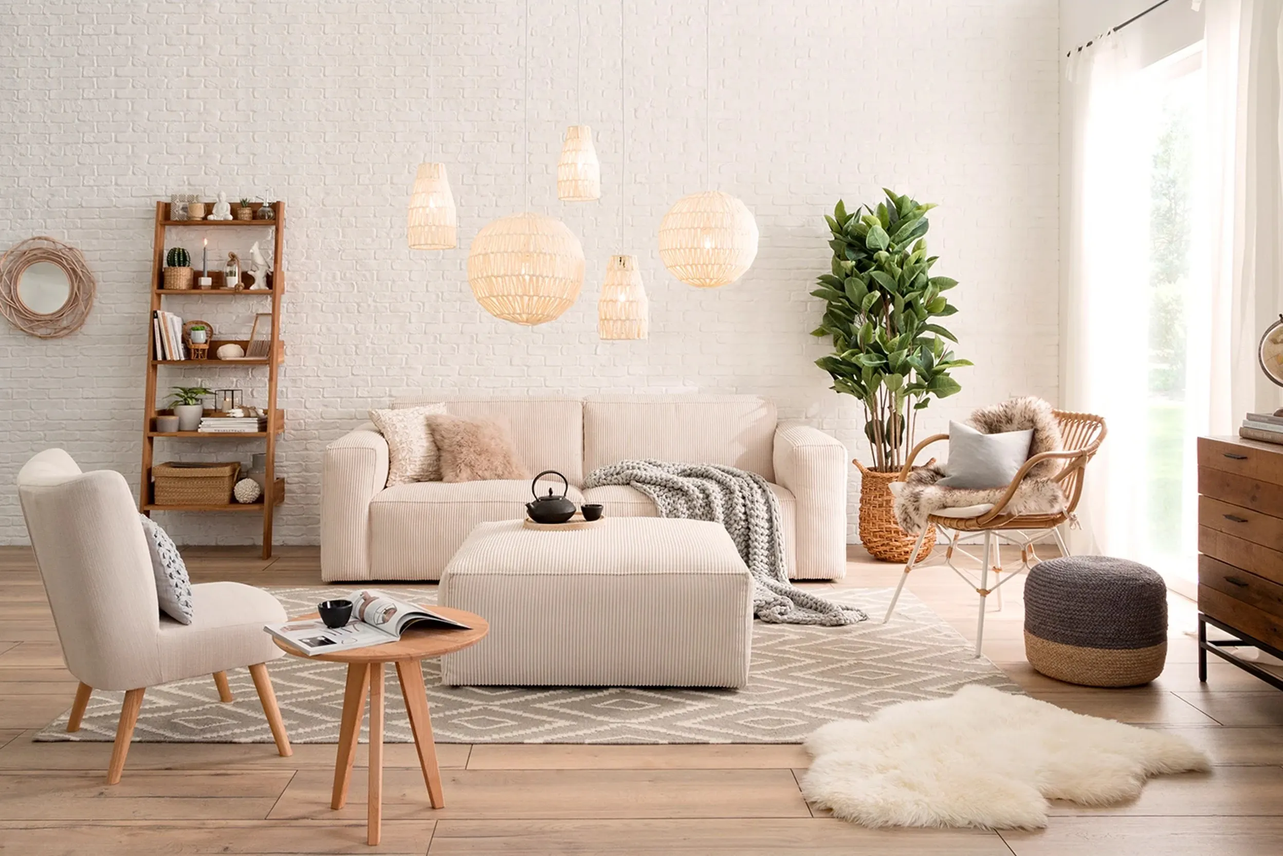 immagine di un soggiorno aperto arredato in colori neutri come crema e beige. Divano poltrona e pouf sono in tessuto beige, Ci sono altri mobili color legno. Le pareti sono dipinte in bianco sporco. Una delle poltrone é in rattan.