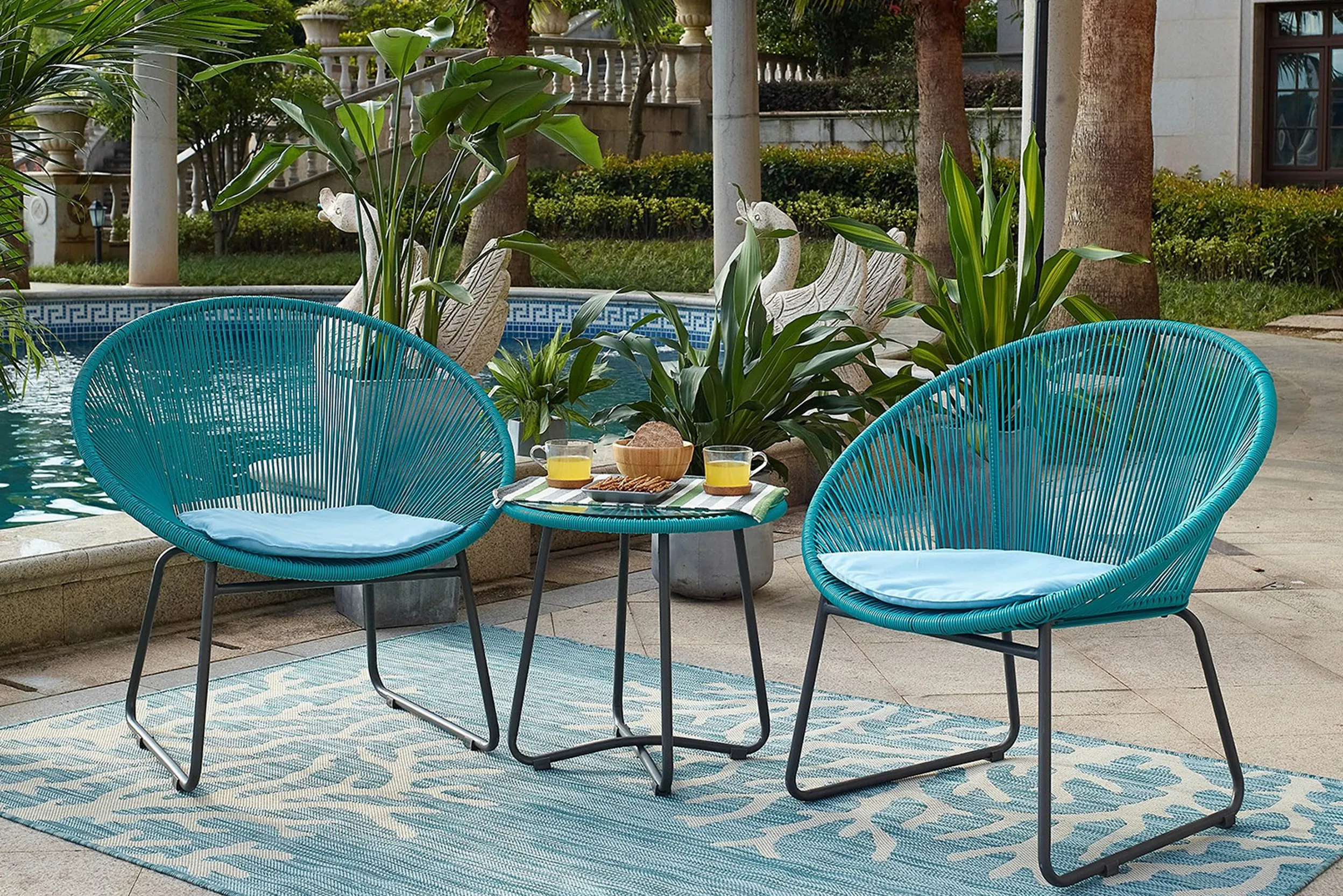 Türkisfarbenes Lounge-Set und Outdoor-Teppich vor einem Pool