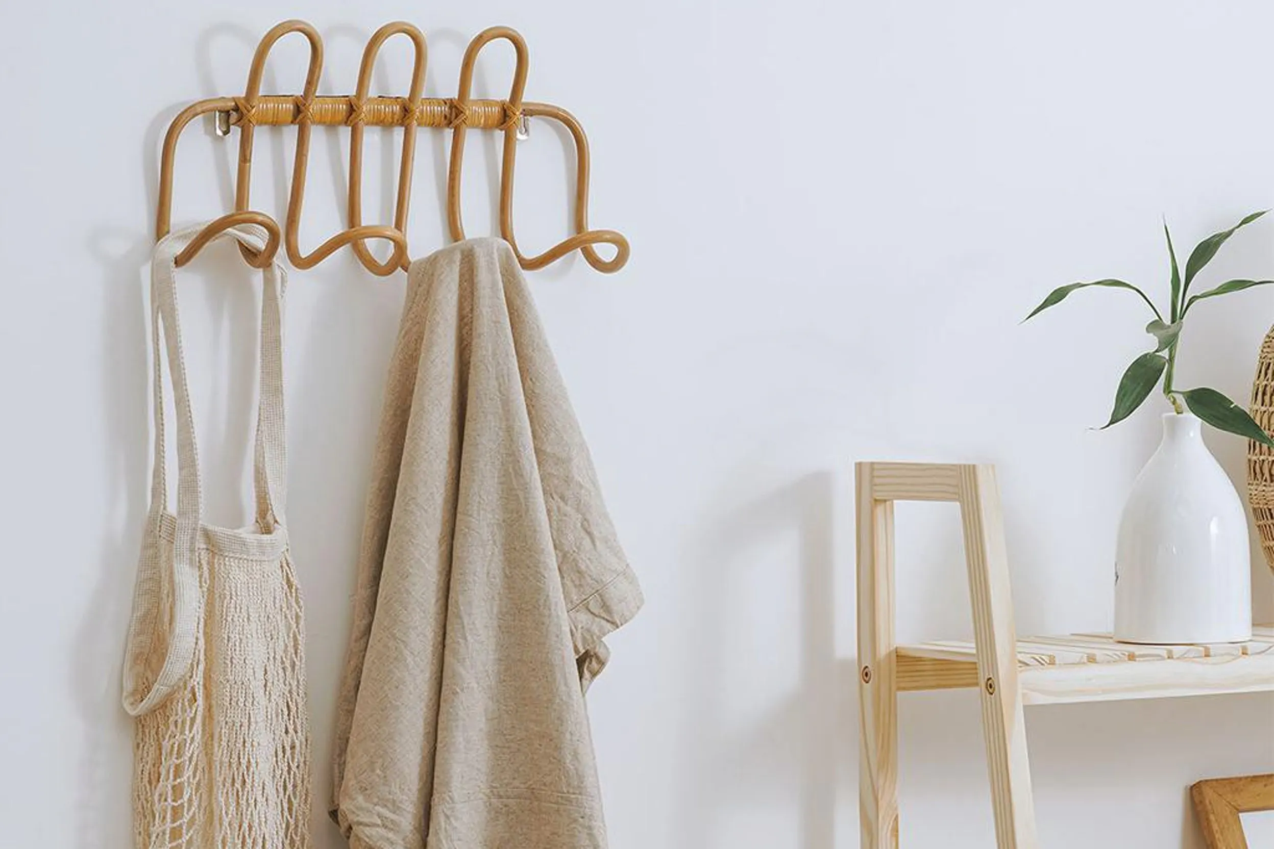 Wandgarderobe aus Rattan neben einem Regal aus hellem Holz