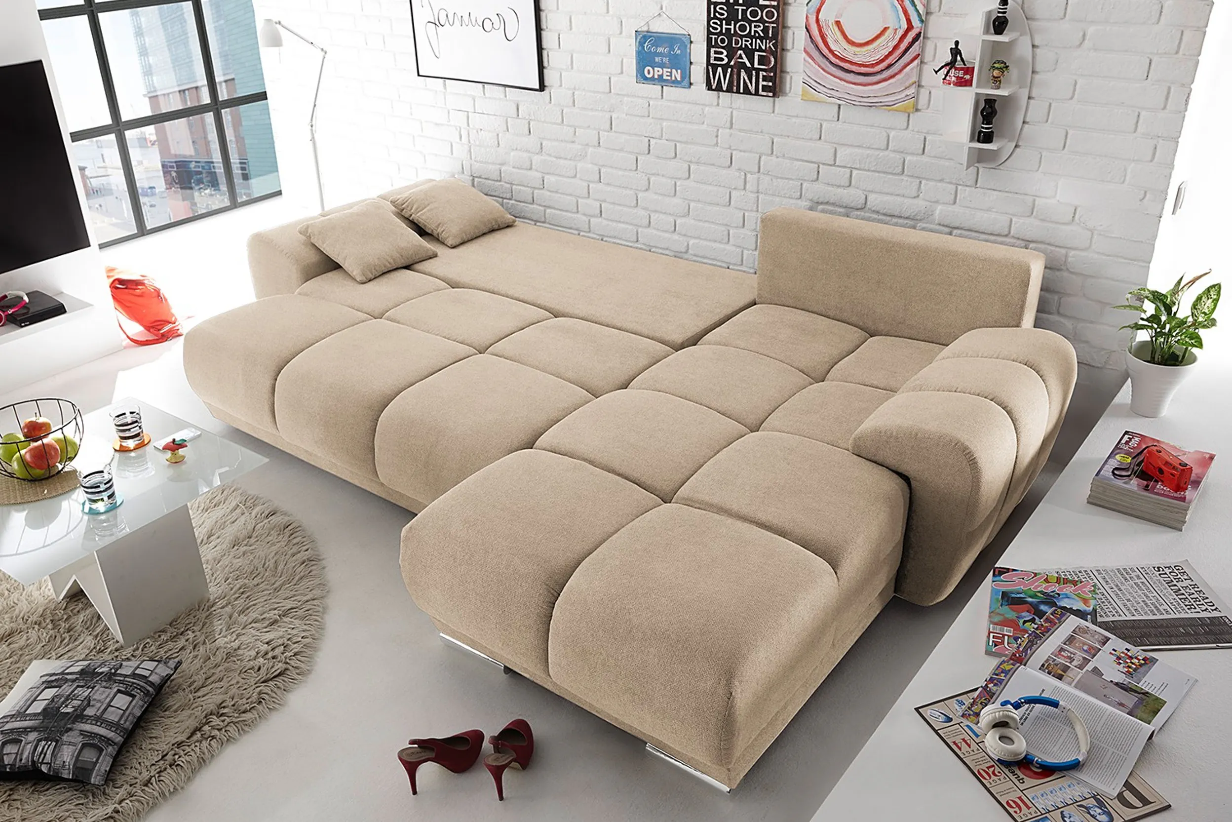 Ausgeklapptes Schlafsofa in Beige vor weißer Backsteinwand
