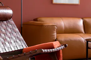 Fauteuil en cuir marron foncé avec appui-tête confortable à côté d'un lampadaire LED en métal noir