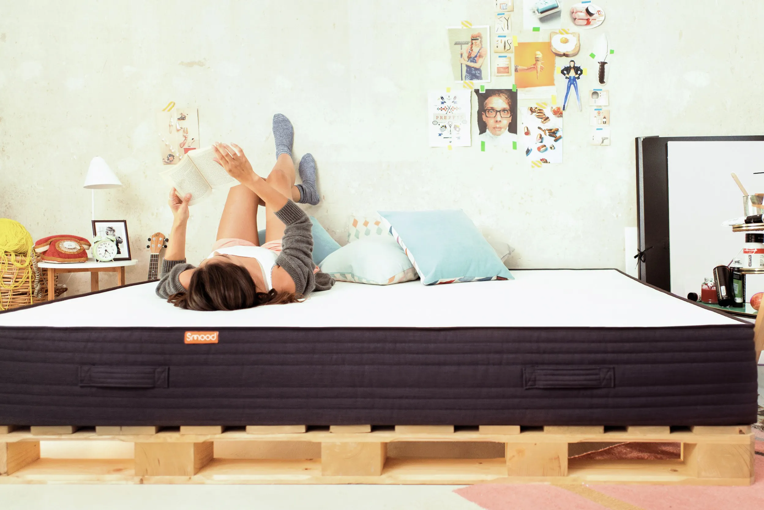 Auf dem Rücken liegende Frau mit einem Buch auf einer Matratze