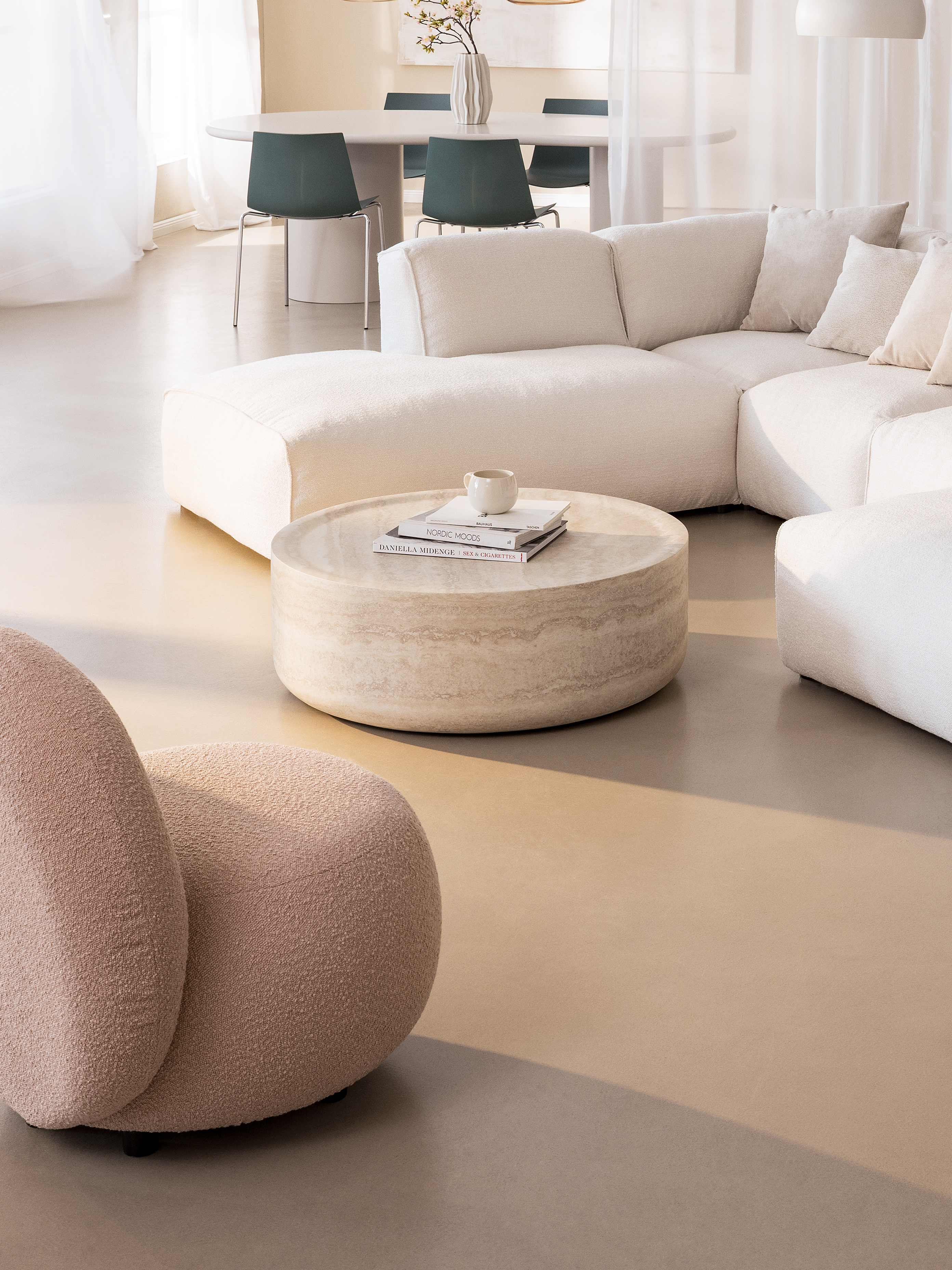 Schlichtes Wohnzimmer mit weißer Couch, rundem Marmor-Couchtisch und kugeligem Plüsch-Sessel.