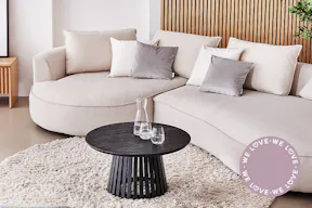 Wohnzimmer in Neutrals zeigt das cremefarbene Sofa Buckley mit gerundetem Polster und rundem Couchtisch aus schwarzem Holz.