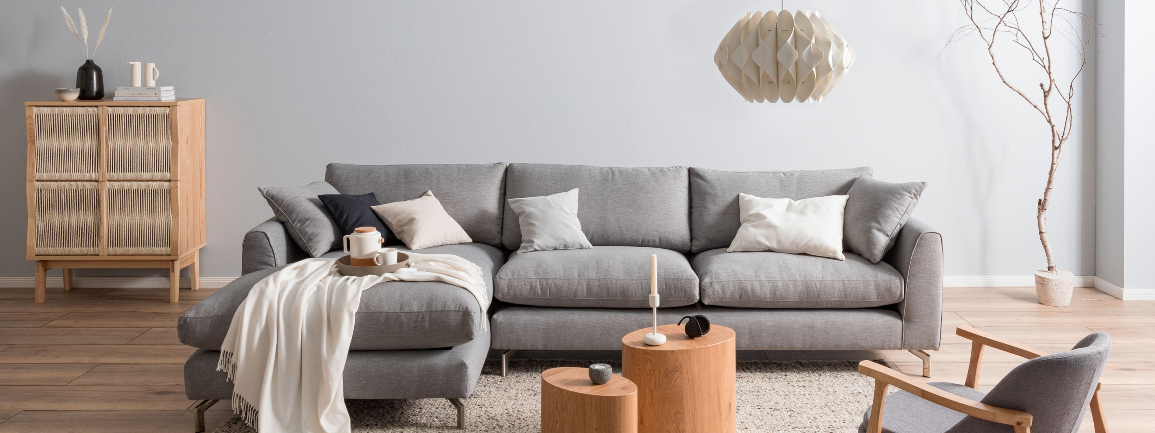 Graues Sofa mit hellen Holzmöbeln im Japandi-Stil