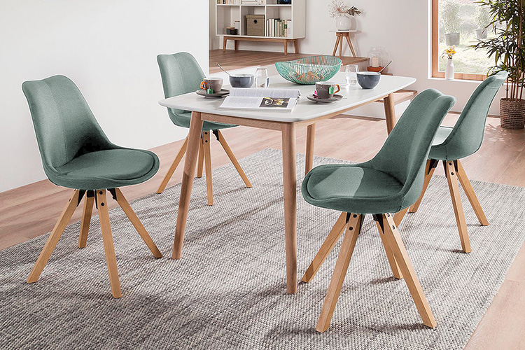 Salle à manger scandinave avec chaises capitonnées colorées aux pieds en bois évasés et table blanche avec pieds en bois de la série Aledas par Mørteens.