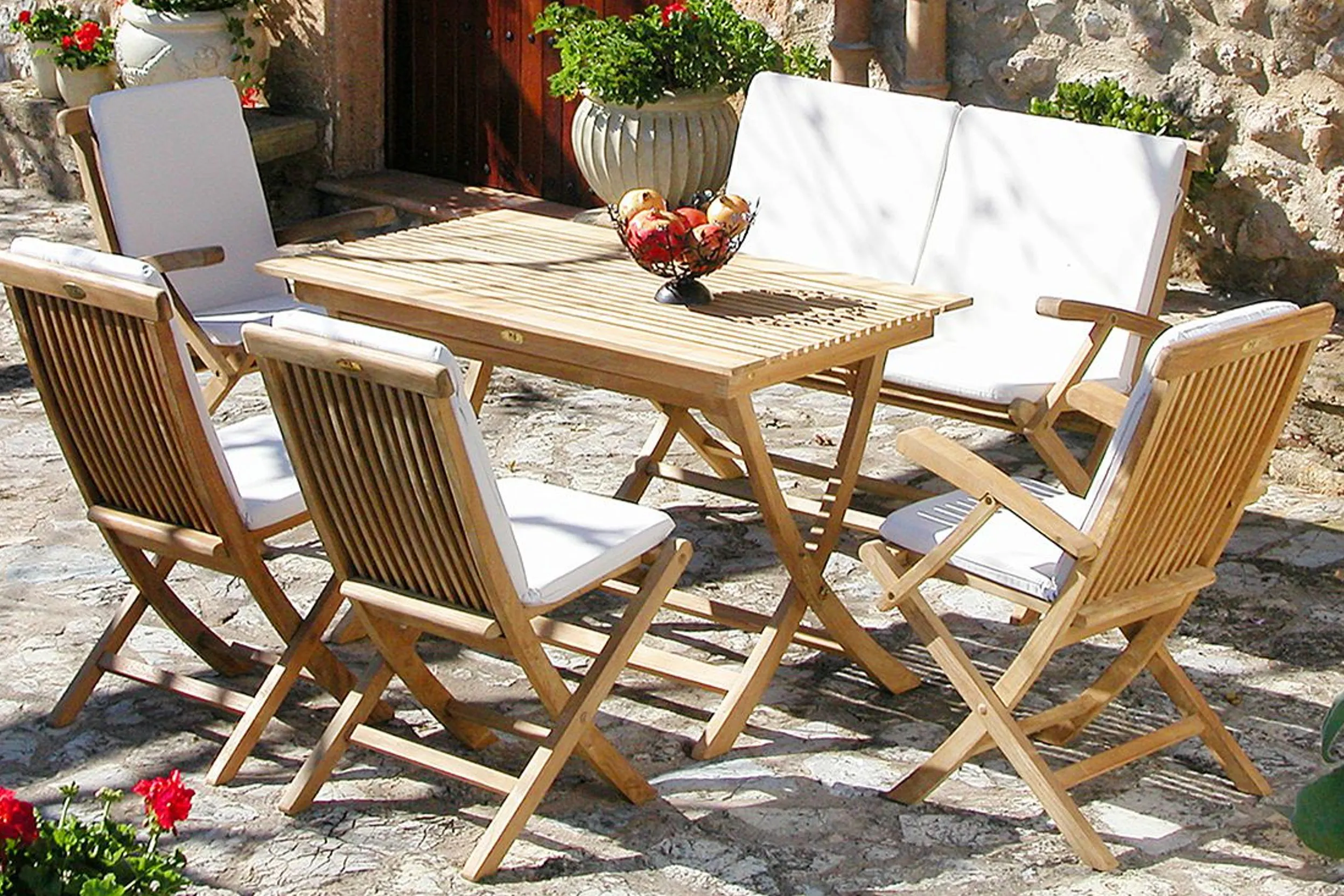 Sitzgruppe aus Teak im Garten bestehend aus vier Stühlen und Gartenbank mit Sitzpolster sowie Klapptisch