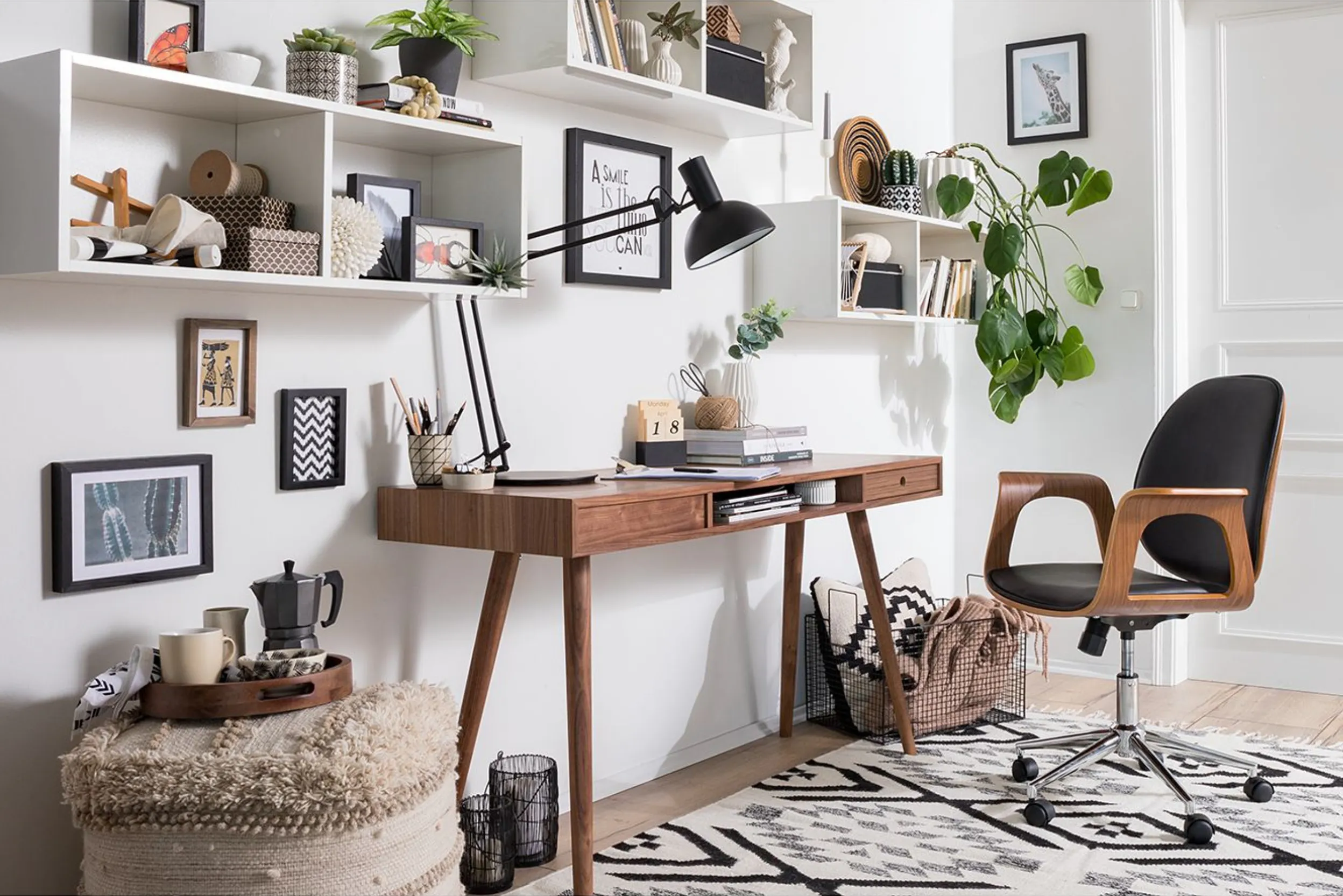 Schreibtisch aus Holz mit vielen weißen, gut bestückten Wandregalen