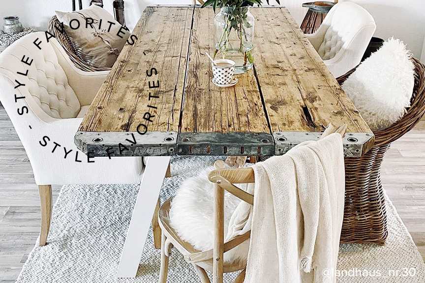 Esszimmer im Landhausstil mit Esstisch aus unbehandeltem, rauem Holz, Esszimmerstühlen aus dunklem Rattan sowie weißen Stühlen mit Chesterfield-Knöpfung