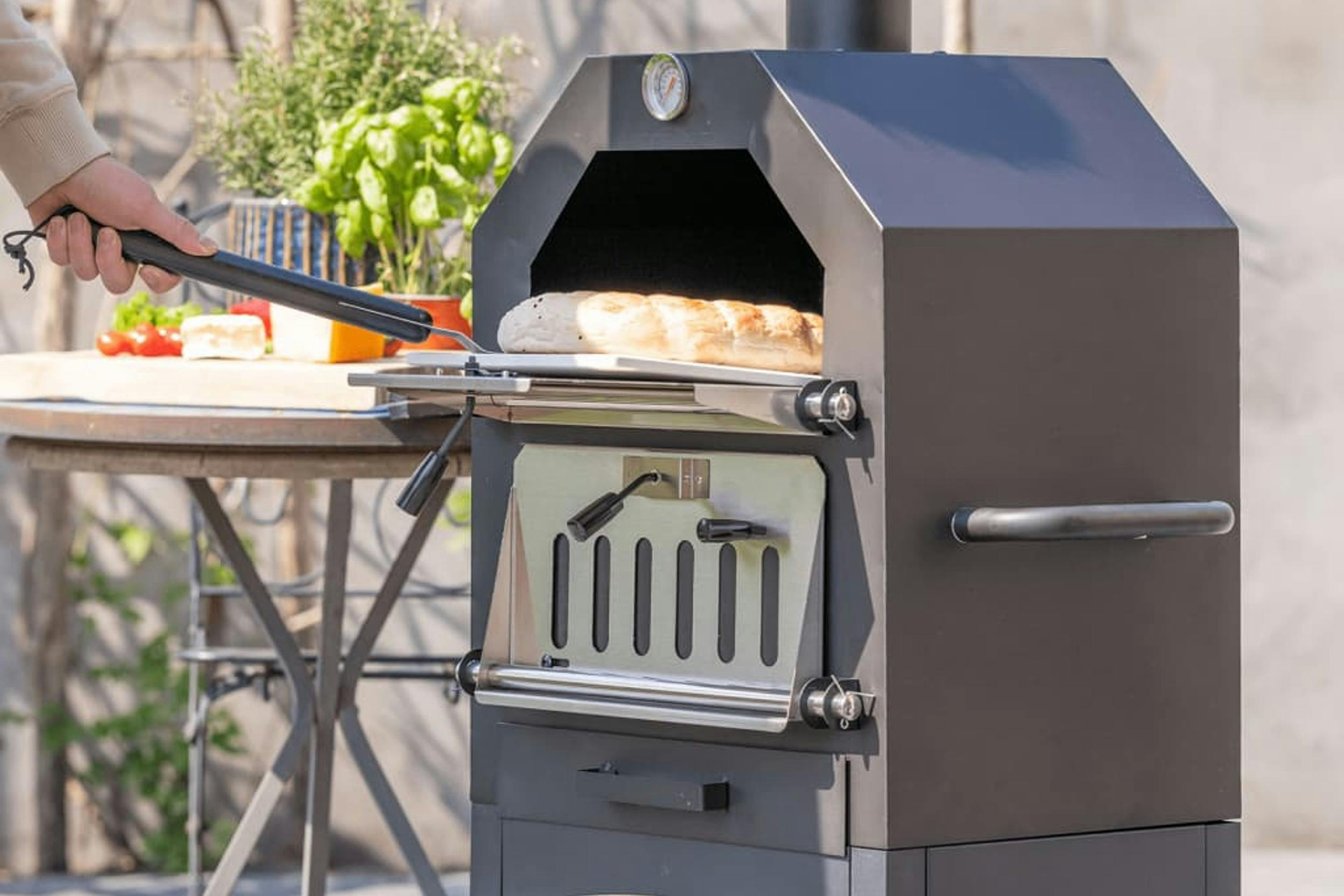 Pizzaofen auf einer Terrasse wird mit Brot zum Backen beladen