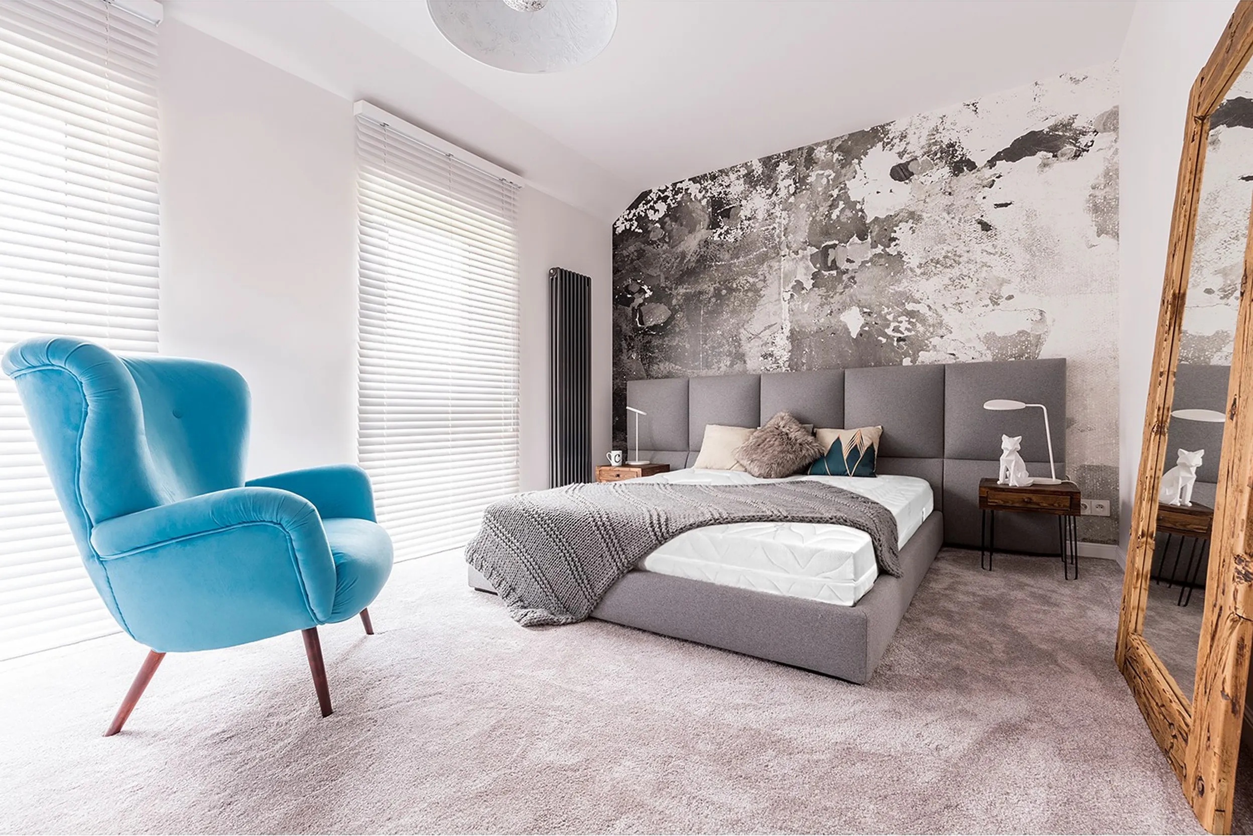 Modernes Schlafzimmer mit großem Bett und blauem Ohrensessel