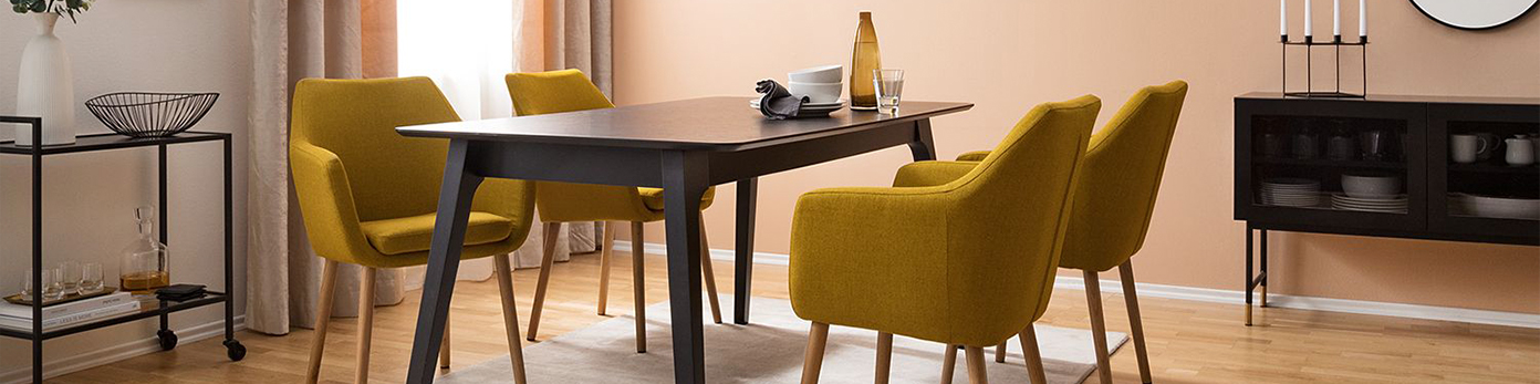 Senfgelbe Polsterstühle am schwarzen Tisch im skandinavischen Wohnstil