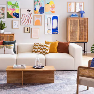 Farbenfroh eingerichtetes Wohnzimmer mit beiger Couch und Echtholzmöbeln.