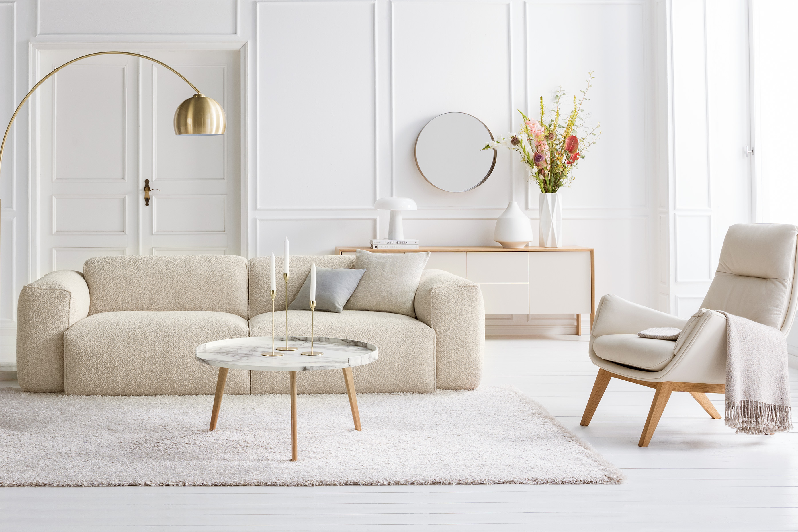 Creme-Wohnzimmer mit weißem Teppich, beigem Sofa und hellen Möbeln.