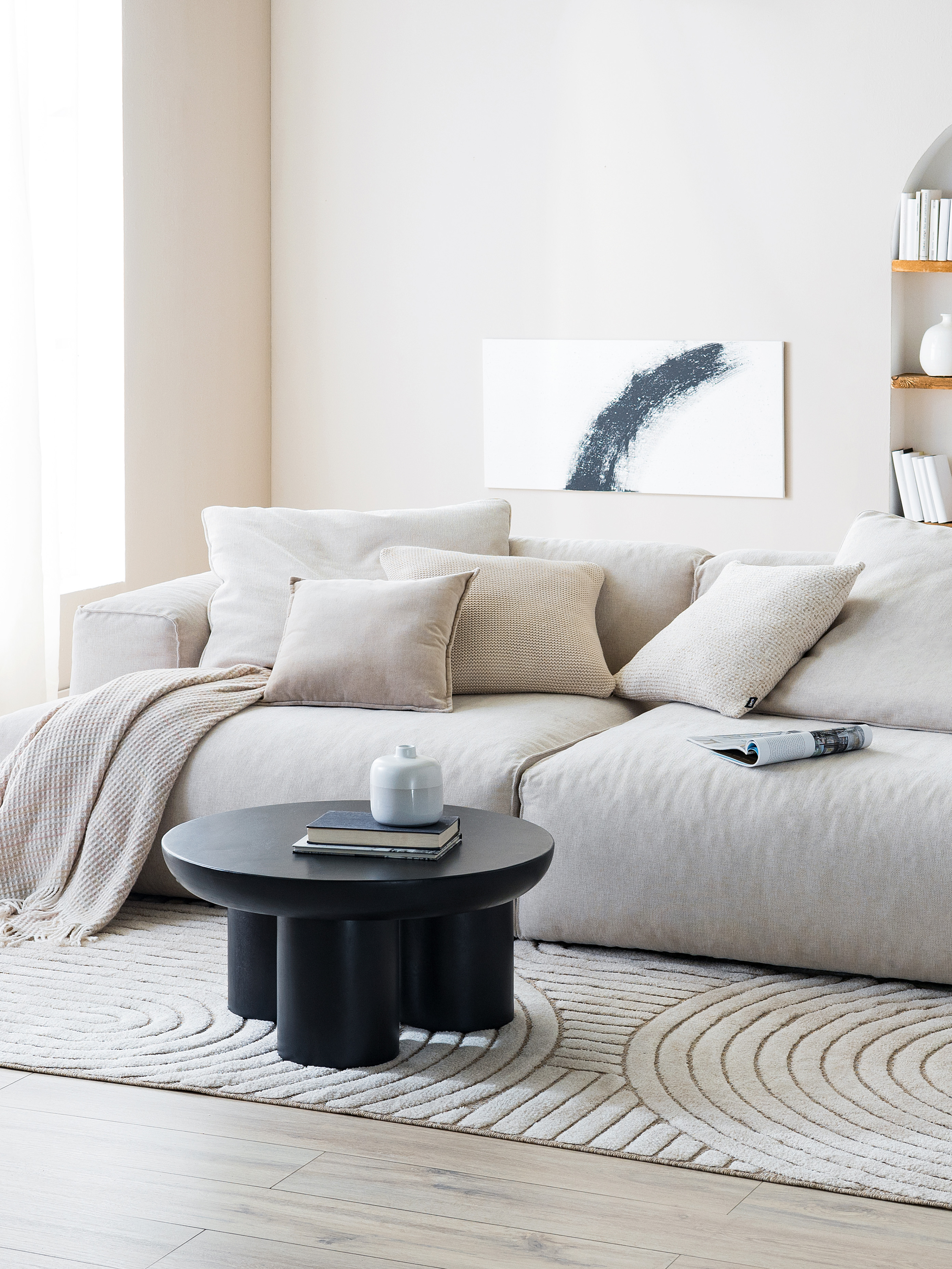Wohnzimmer in kühlen Farben, grauem Sofa und schwarzem Couchtisch.