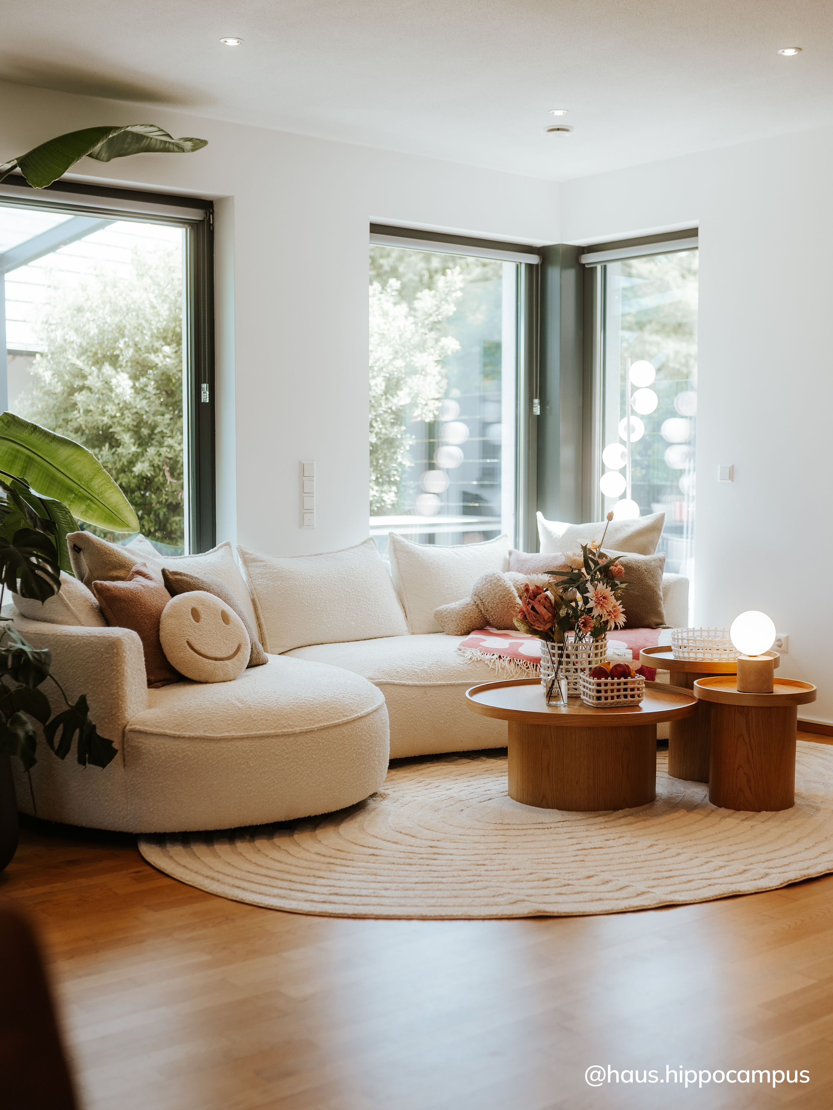 Gemütliches, helles Wohnzimmer mit beigem Sofa und Couchtisch-Zweierset aus Holz.